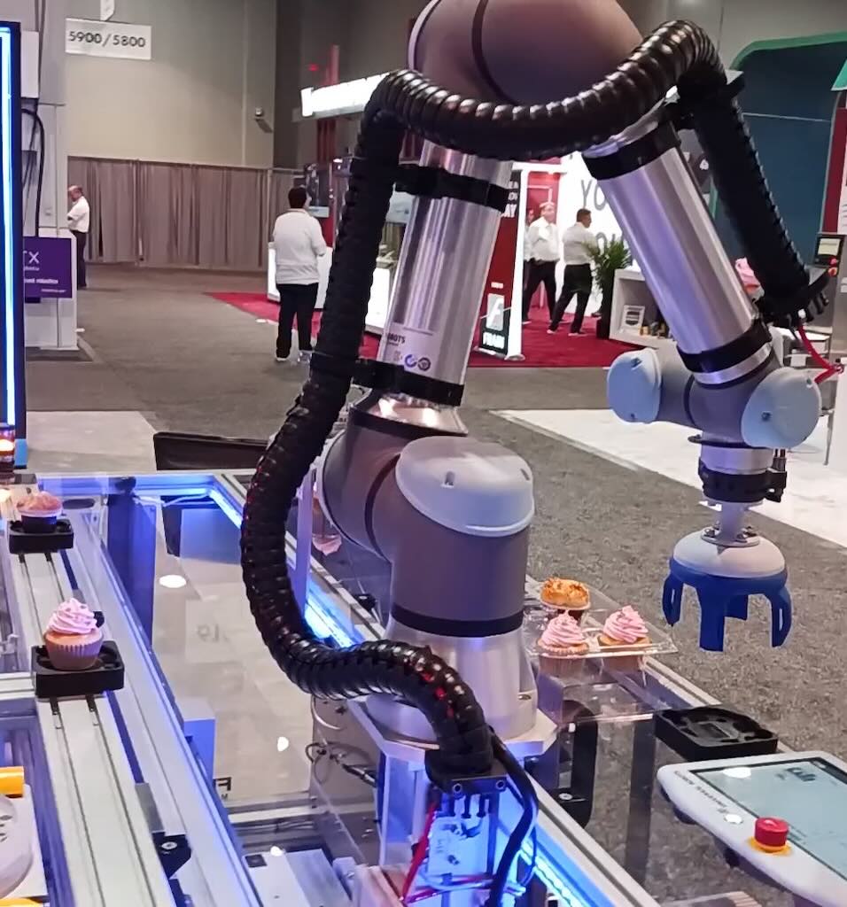 Festo Corp. demonstration at Pack Expo Las Vegas 2023 shows a Universal Robots UR5 whose reach to grab cupcakes is extended with a slide (see other photo) and motor. The Universal Robots collaborative robot software integrates the extra access of motion seamlessly. Courtesy: Mark T. Hoske, Control Engineering